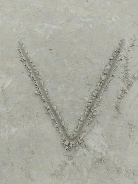 A sharp letter V etched into flat sandy ground Stock Photos