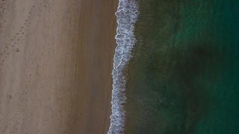 Sharp line of white waves breaking between the dark sand and the deep water Stock Photos