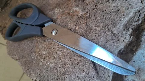 Sharp metal scissors on a stone surface. Steel cutting tool for craft and office Stock Photos