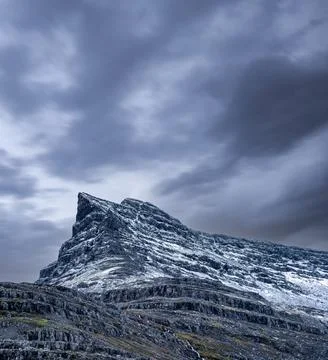 Sharp mountain peak under cloudy sky on winter Stock Photos