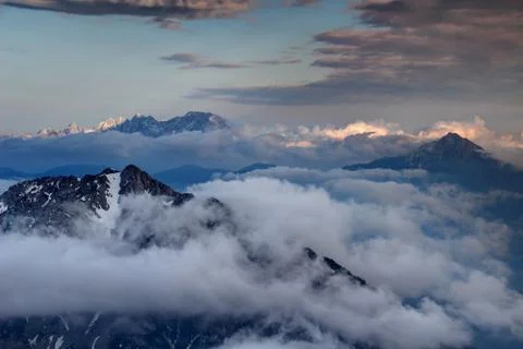 Sharp peaks Karavanke range and Kamnik Alps rise above clouds Stock Photos