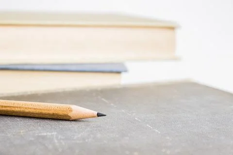 A sharp pencil with book over the light background. 库存照片