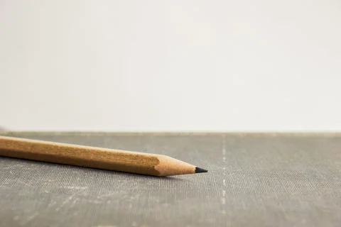 A sharp pencil with book over the light background. Stock Photos
