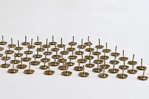 Sharp pins pointing upwards on blurred white background Stock Photos