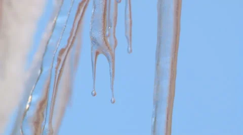 Sharp pointed melting icicles drip under clear blue sky - Closeup Stock Footage 47720790