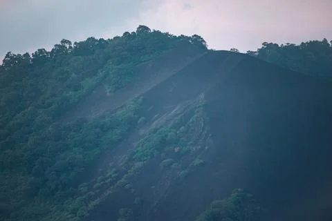Sharp Ridge of Black Volcanic Ash Slope Meeting Lush Green Tropical Forest Stock Photos