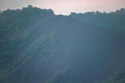 Sharp Ridge of Black Volcanic Ash Slope Meeting Lush Green Tropical Forest Stock Photos