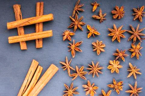 Sharp scattered cinnamon left and star anise right top view on slate Stock Photos