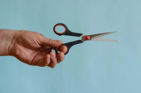 Sharp scissors with black and red arms in a male hand. Stock Photos