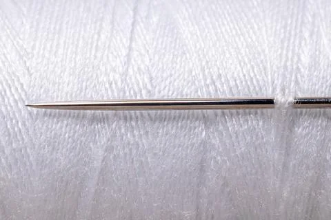 Sharp sewing needle on white thread spool background macro Foto stock