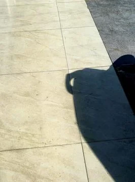 Sharp Shadow of Motorcycle Seat on Beige Ceramic Tile Floor Stock Photos