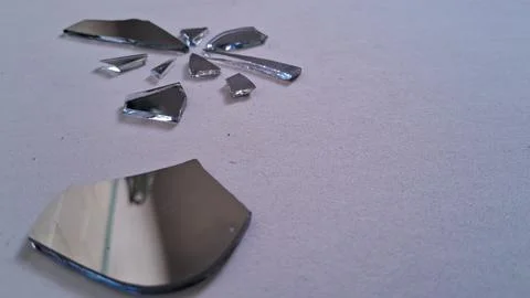 Sharp shards of broken glass mirror scattered across white surface background Stock Photos