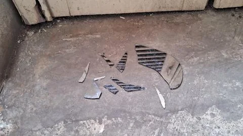 Sharp shards of broken glass scattered on the weathered concrete floor Stock Photos