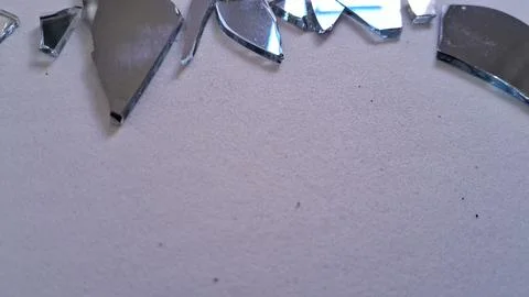Sharp shards of broken mirror glass scattered on white surface Stock Photos