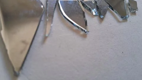 Sharp shards of broken reflective mirror scattered on white surface texture Stock Photos