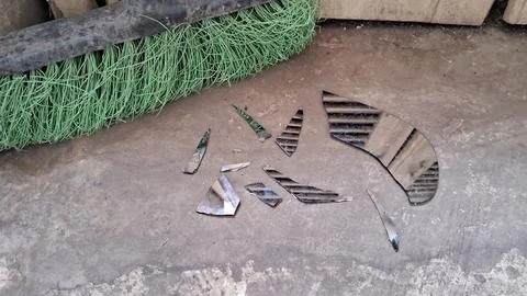 Sharp shattered glass pieces lying on a dirty concrete floor surface Foto stock