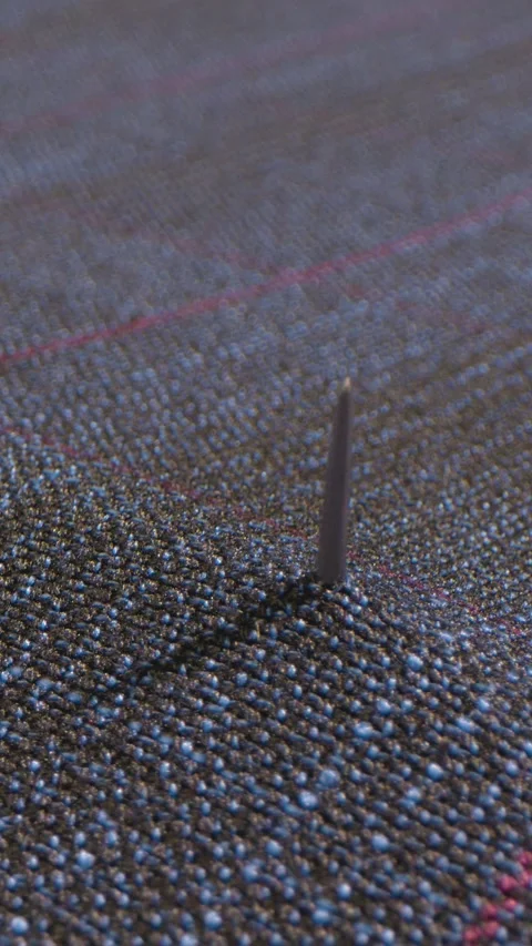 Sharp silver sewing needle piercing textured blue windowpane plaid fabric Stock Footage 326477969