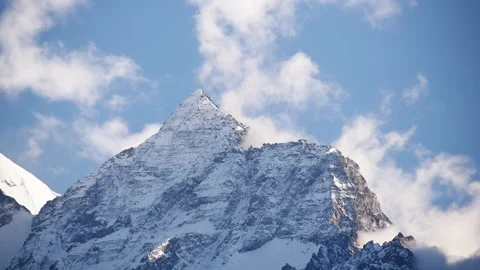 Sharp snow-capped pyramid of the Nilgiri ridge piercing drifting cloud, Upper Vidéo 344530589