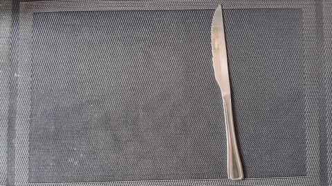 Sharp stainless steel serrated dinner knife resting on textured surface Stock Photos