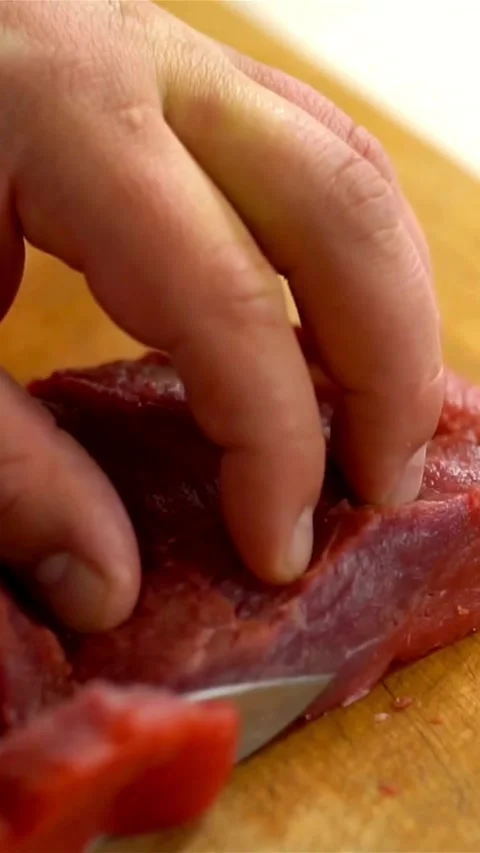 Sharp steel knife slices fresh raw beef on board Video stock 334169648