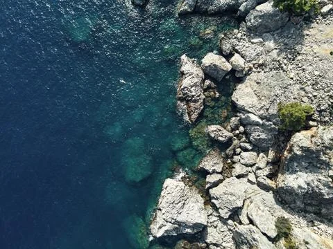 Sharp stones and rocks in the turquoise, blue sea. Drone aerial shot from above Stock Photos