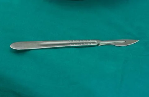 A sharp surgical blade on green table Stock Photos
