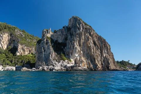 Sharp tall rocky cliffs visible above water - typical seascape near Paleoka.. Fotos Stock