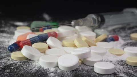 Sharp tip of a medical needle with pills on the background and Pharmaceutical Stock Footage 263744189