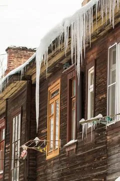 Sharp transparent icicles hang on the edge of the roof. Stockfoto's