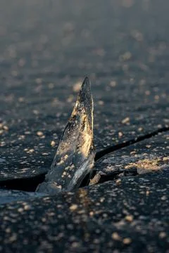 A sharp triangular piece of ice illuminated by sunset light, vertical frame.  Stockfoto's