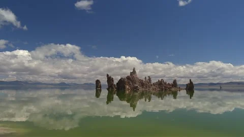 Sharp tufa formations reflected clearly in still green lake water with Stock Footage 328470934