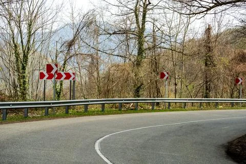 Sharp turn and warning signs in mountainous terrain Foto stock