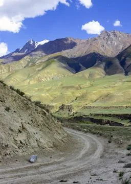 Sharp turn of the dirt road into a narrow mountain valley. Stock Photos