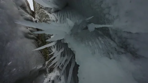 Sharp white icicles hang on ceiling inside grotto. Frozen stalactites Stock Footage 166566062