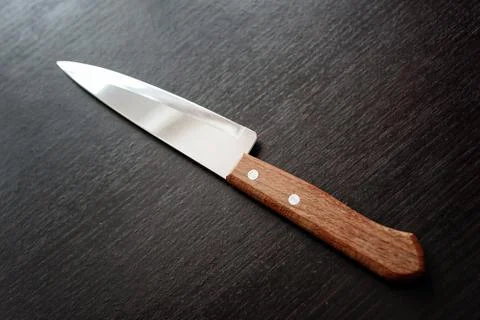 Sharp wooden handled kitchen knife with silver chrome blade and edge on a bla Stock Photos