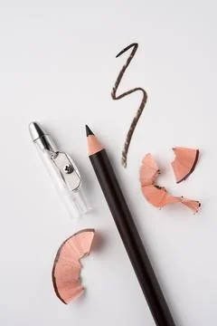 Sharpened brown eyeliner pencil with sharpener and cosmetic shavings on white Stock Photos