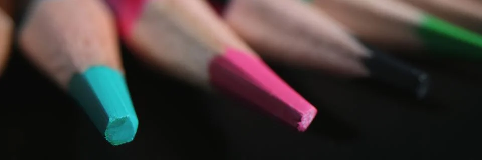 Sharpened multi-colored pencil tips on dark background Stock Photos