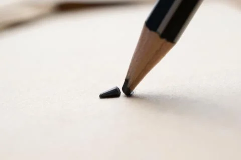Sharpened pencil over a blank old sheet of paper with a broken tip. Stock Photos