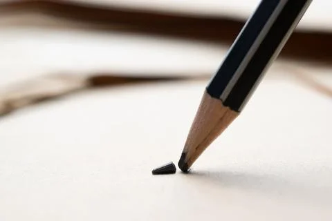 Sharpened pencil over a blank old sheet of paper with a broken tip. Stock Photos