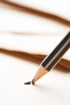 Sharpened pencil over a blank old sheet of paper with a broken tip. Stock Photos