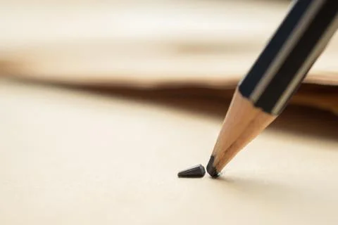 Sharpened pencil over a blank old sheet of paper with a broken tip. Stock Photos