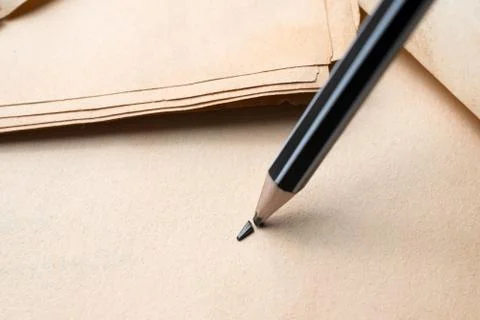 Sharpened pencil over a blank old sheet of paper with a broken tip. Stock Photos