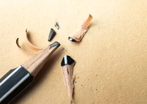 Sharpened pencil over a blank old sheet of paper with a broken tip. Stock Photos