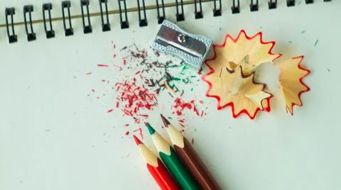A sharpener and three colored pencils on a notepad Stock Photos