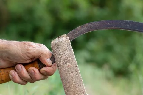 Sharpening the blade of an hand braid. A man sharpens the blade of an old r.. Stock Photos