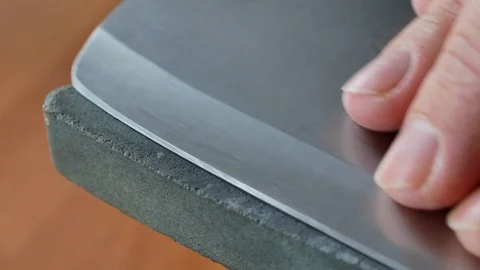Sharpening butcher chopping knife on grindstone Stockbeeldmateriaal 103084801
