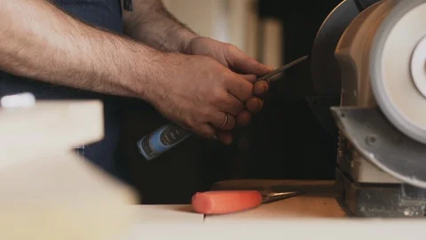 Sharpening a chisel on grinding machine with sparks fly Stock Footage 89303812
