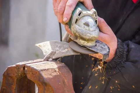 Sharpening garden tools hoe using grinder close-up, Machine for grinding / we Stock Photos