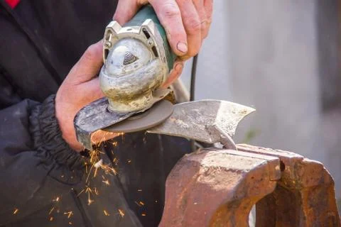 Sharpening garden tools hoe using grinder close-up, Machine for grinding / we Stock Photos