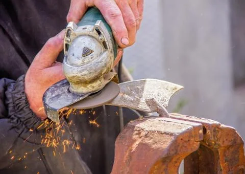 Sharpening garden tools hoe using grinder close-up, Machine for grinding / we Stock Photos